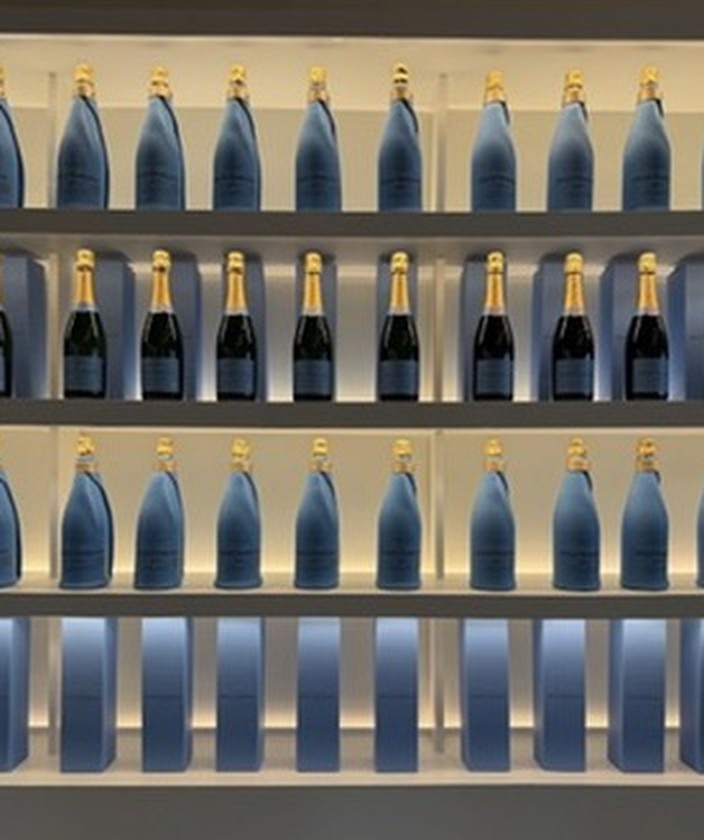 Backlit shelves of Petit Domaine sparkling wine bottles